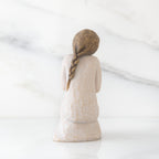 Back view of kneeling female figure in cream dress, with wire butterfly on extended hands