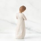 Back view of brown hair girl figurine standing in white dress