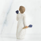 Back view of brunette girl figurine in white dress holding blue flowers