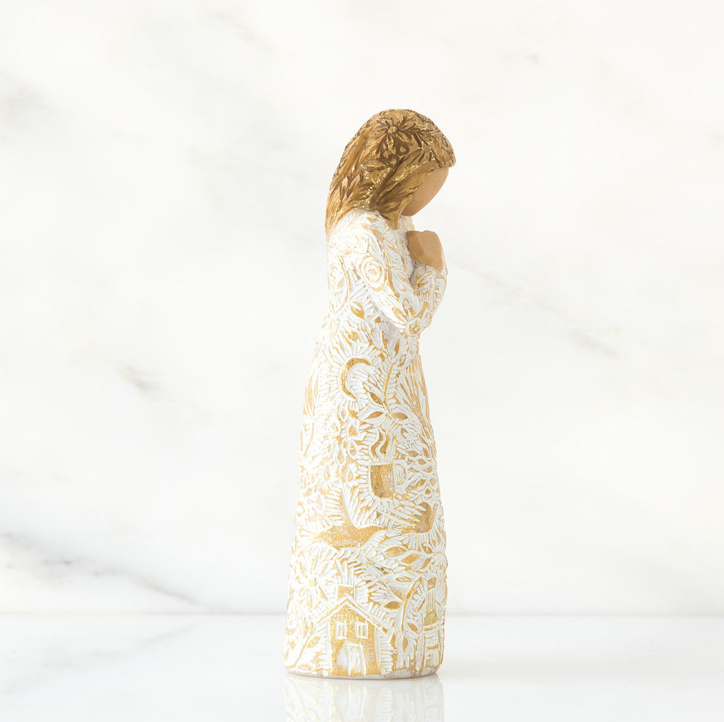 Gold haired girl figurine in white / gold dress facing the side holding her hands to her chest - white background