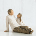 Man figurine and daughter faceless figurines sitting looking at one another - wearing white shirts and brown pants