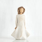 Faceless girl figurine with brown curly hair wearing white dress facing forward