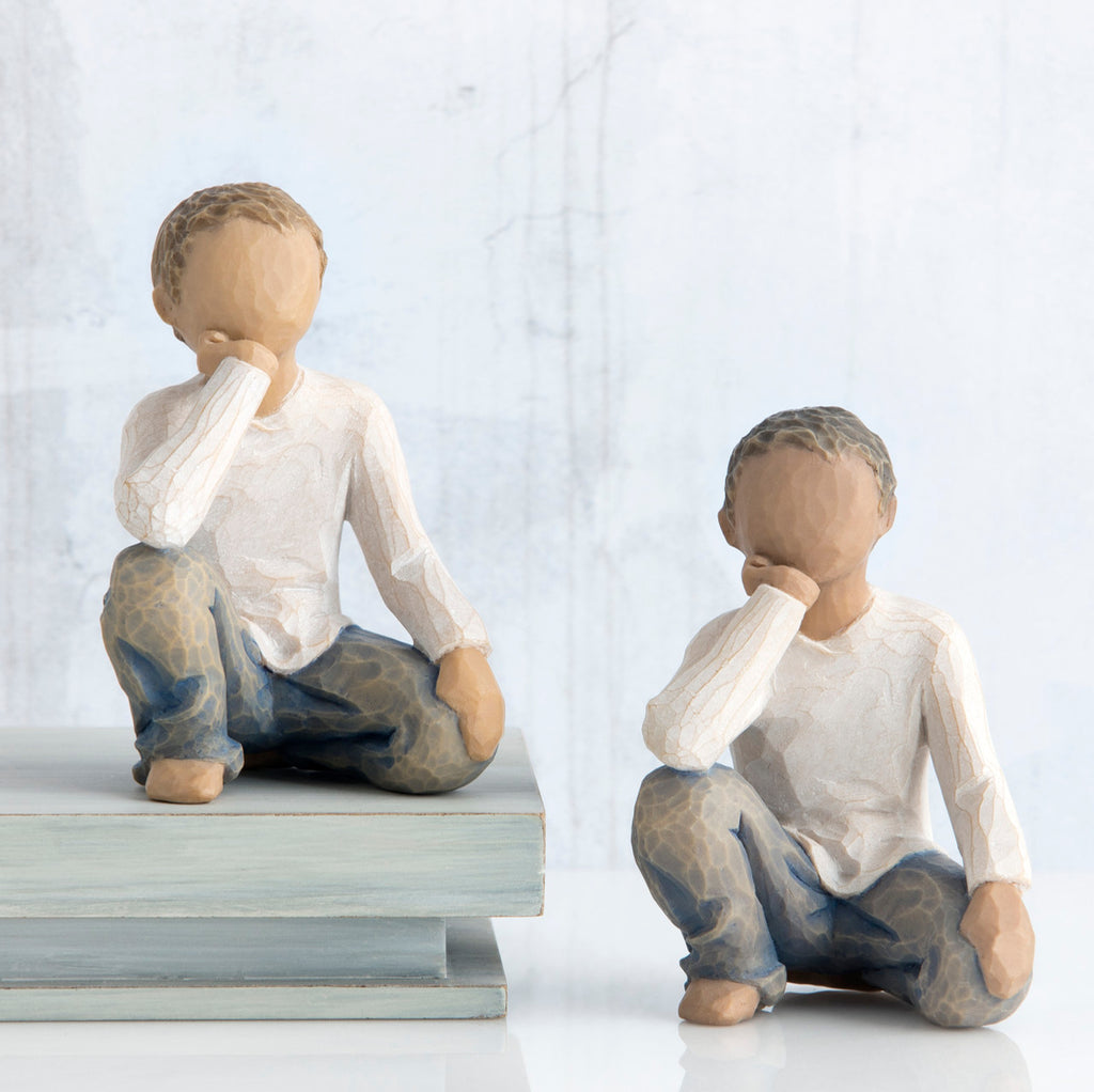 Set of two boy figurines in white shirts and blue jeans with their hands on their face