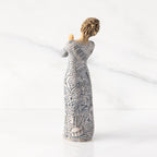 Back view: Lighter-skin figure carved with contrasting pattern of dark blue musical symbols, instruments, dancing forms