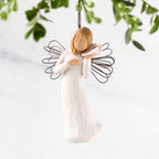Female angel with wire wings in cream dress, holding pink shell up to ear, ornament loop attached to head