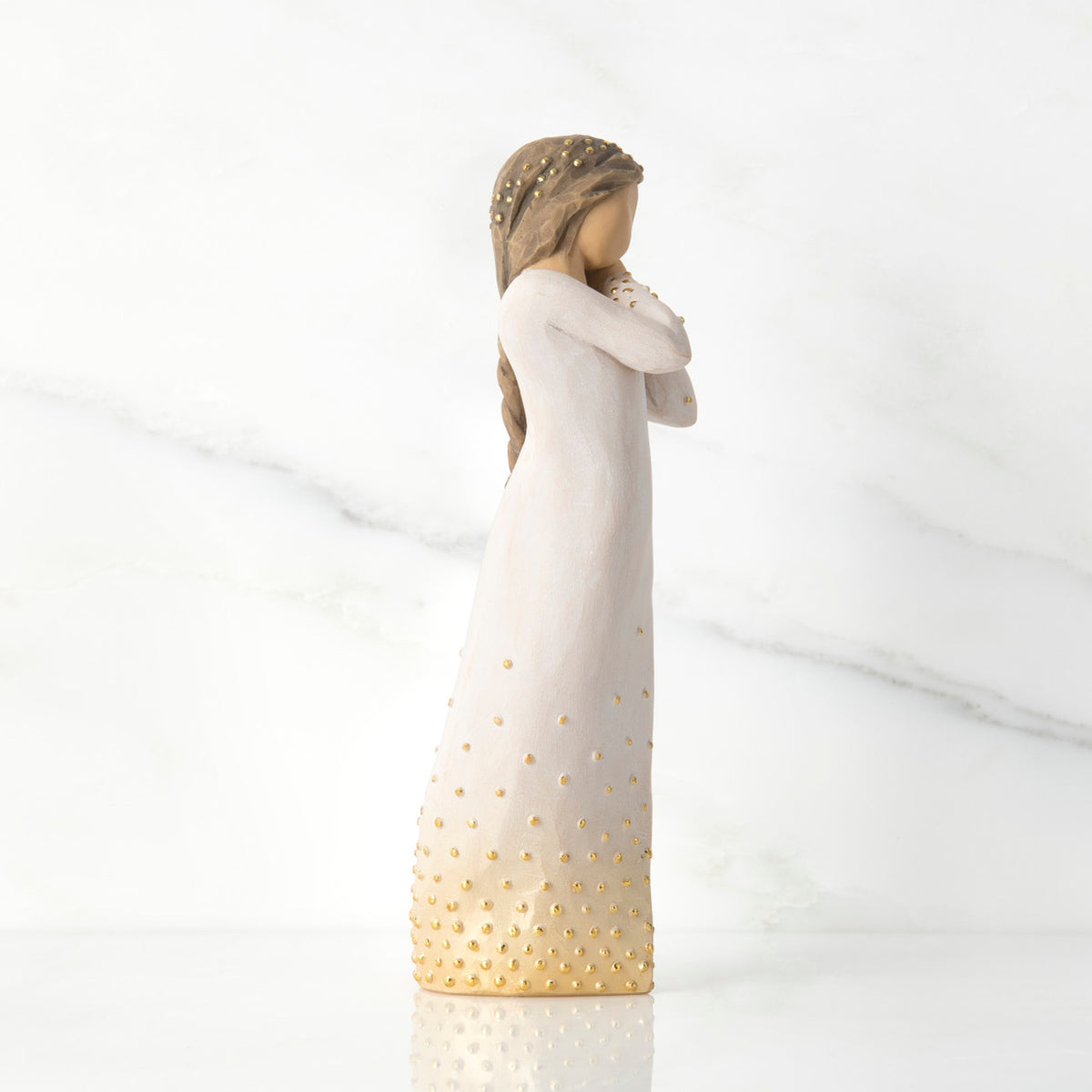 Right-facing view, standing figure in cream dress, holding arms to face in wistful gesture. Hair and dress embellished with gold dots
