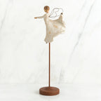 Brunette angel figurine in white dress on wooden stand with her arms out