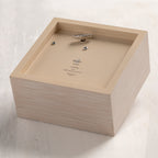 Bottom of cream wood box with hinged lid, showing winding mechanism for music.