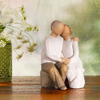 Willow Tree Anniversary, 6”h hand-painted resin figure of older couple sitting on bench holding hands, both in neutral clothing, on wood shelf with wildflowers