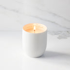 Lit filled scented candle with unglazed cream tapered cylinder vessel, sentiment written in gold inside rim, plant-based wax blend, all-cotton wick