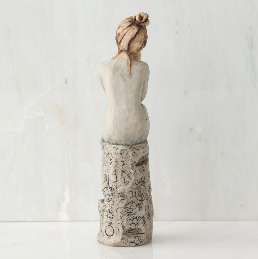 Back view of brunette girl sitting on grey rock
