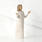 Side view of brunette woman figurine in white dress with gold dots holding her hands up