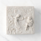 Close-up of white resin box; lid carved with figural and organic imagery