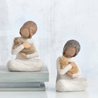 Set of two brunette girl figurines sitting down holding golden cats - all white background