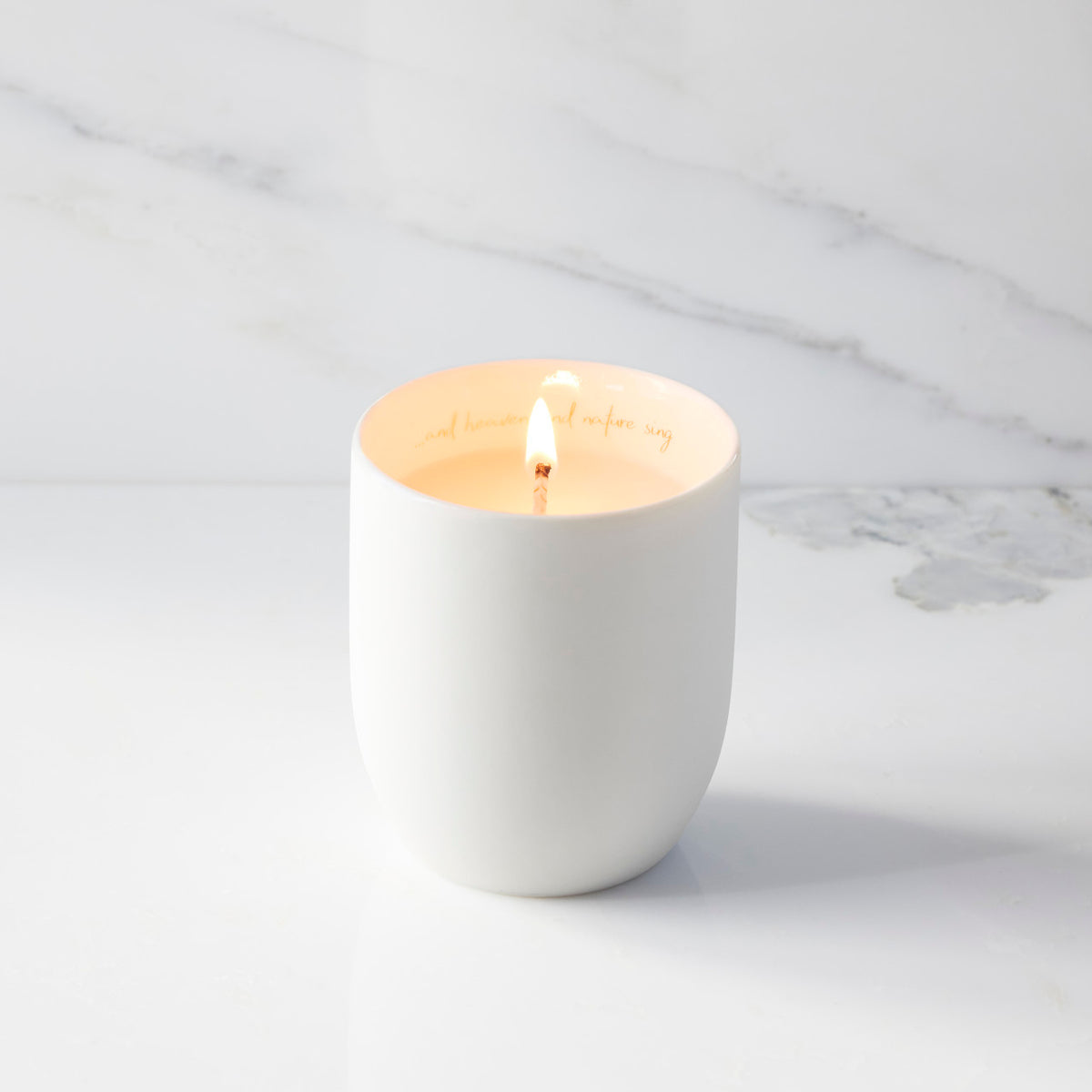 Lit filled scented candle with unglazed cream tapered cylinder vessel, sentiment written in gold inside rim, plant-based wax blend, all-cotton wick