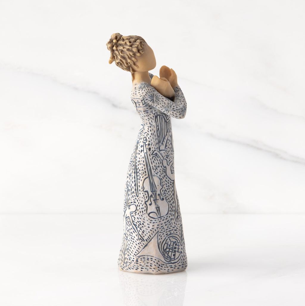 Facing right: Lighter-skin figure carved with contrasting pattern of dark blue musical symbols, instruments, dancing forms