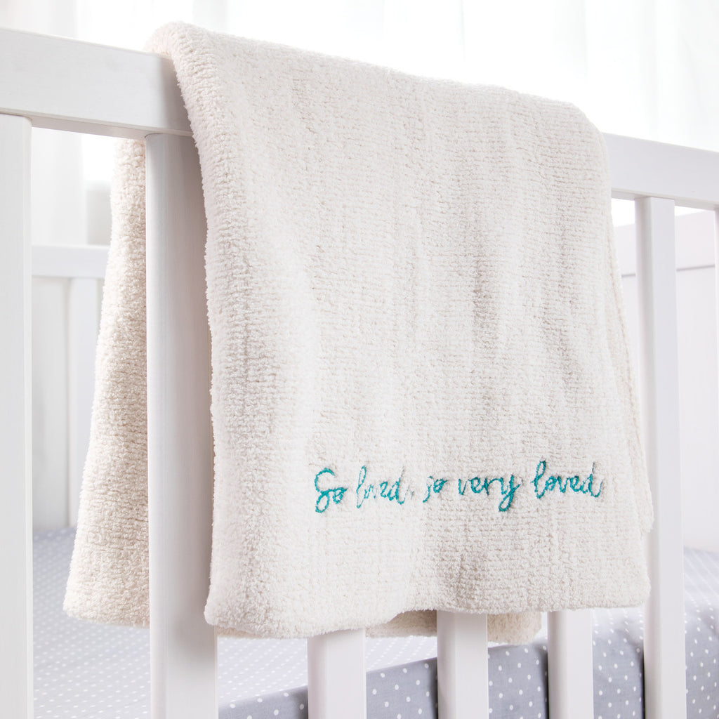 Close view of white towel with 'so loved, so very loved' in blue