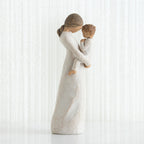 Side view of faceless mom figurine wearing white dress holding child in white outfit in her arms