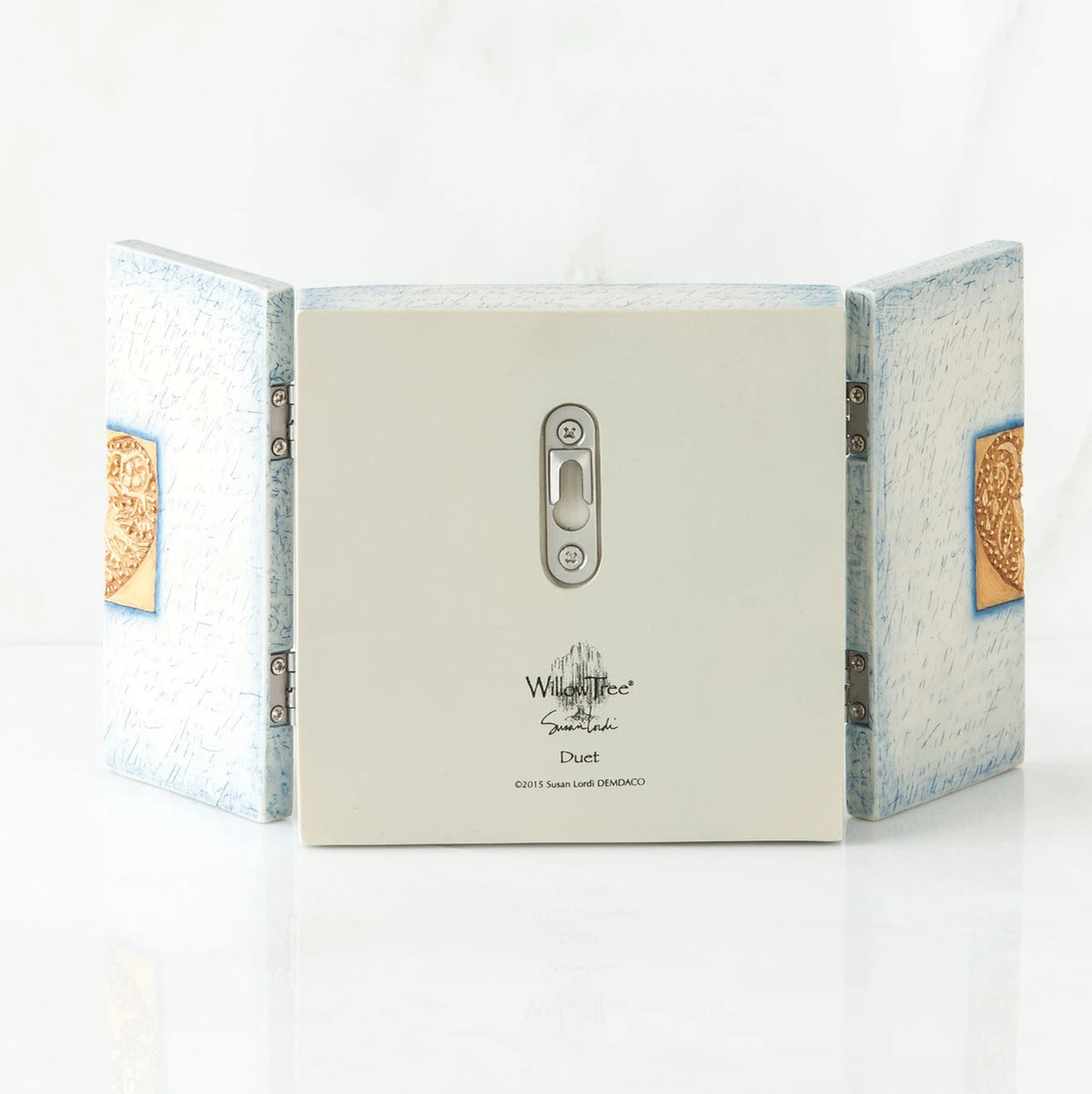 Back side of wooden white/blue book with silver key hole showing and willow tree printed in black