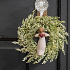 Willow Tree With Love Ornament, 4”h hand-painted resin angel figure with darker hair and skin, in cream dress, wire wings, holding red heart, brown elastic cord, hanging inside spring wreath