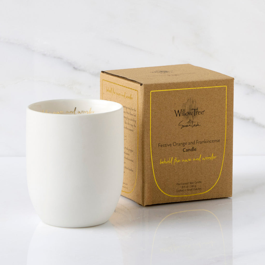 Filled scented candle with unglazed off-white tapered cylinder vessel, sentiment written in gold inside rim, plant-based wax blend, all-cotton wick, shown with packaging