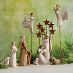 Several wiseman figurines dressed in white around lamb figurines with green background
